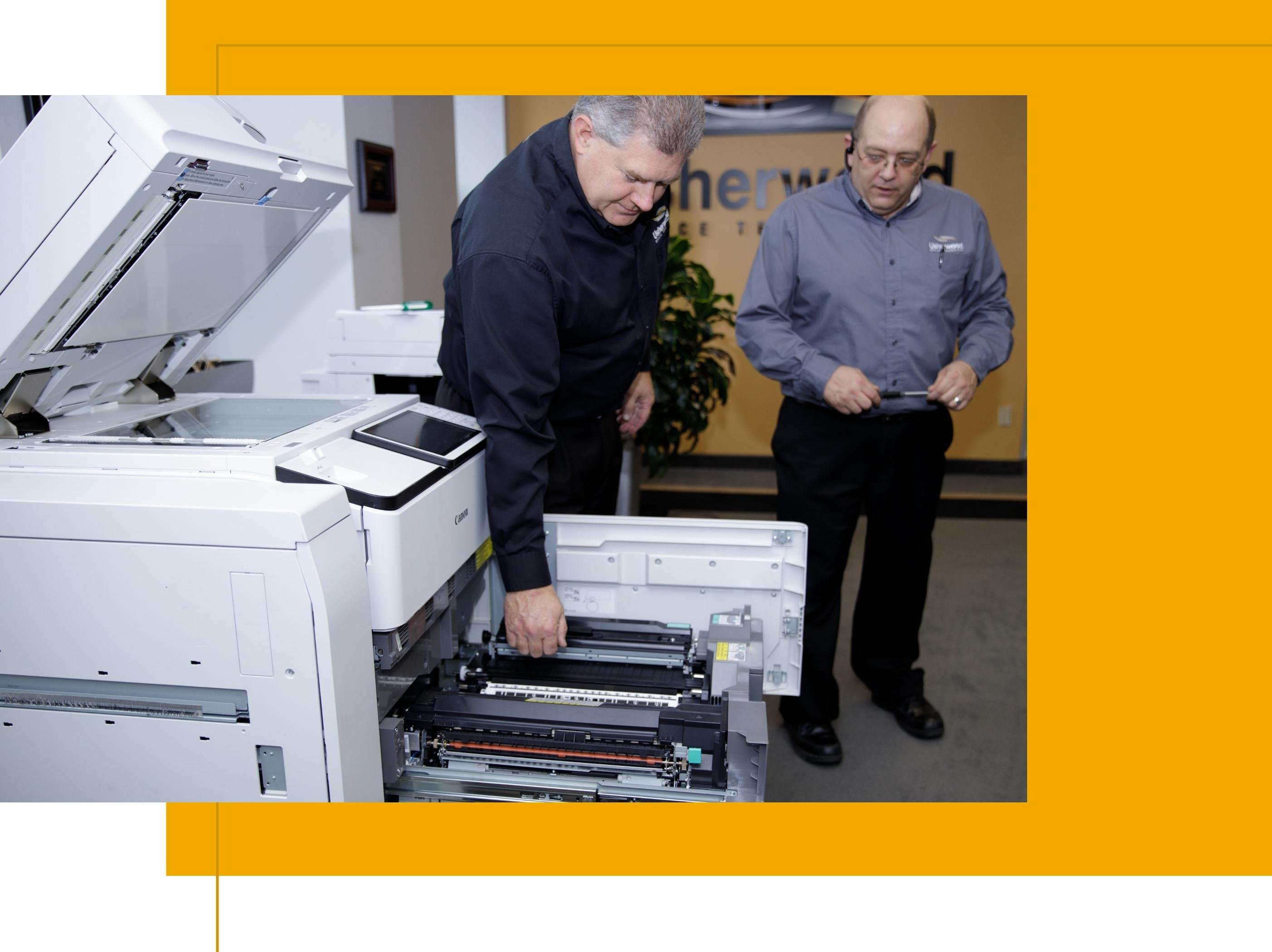 Two technicians looking over an open copier
