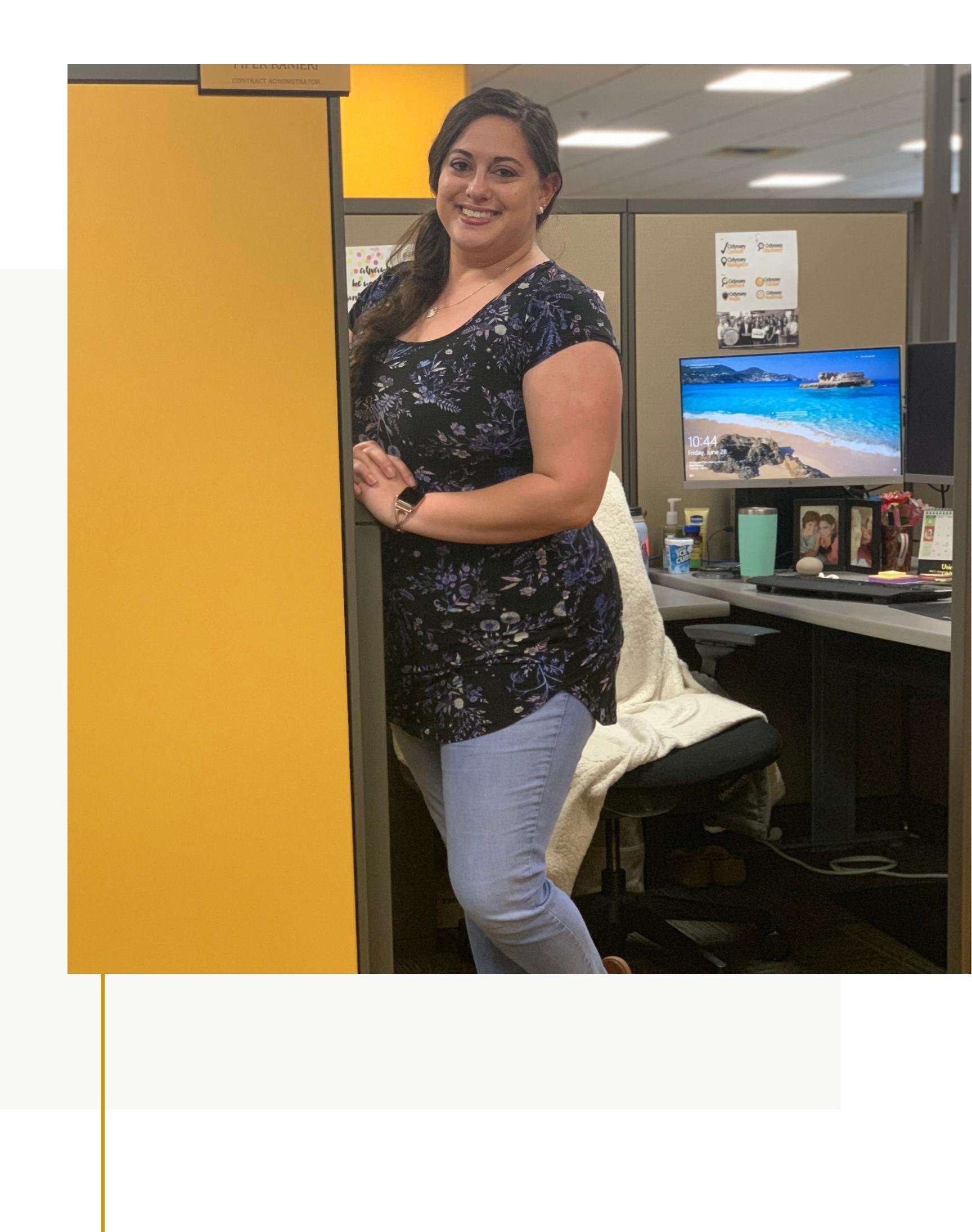 Contracts team member standing in front of desk, smiling