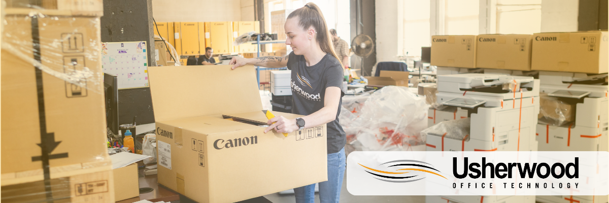 women wearing usherwood shirt unpacking a cannon box with printers in the back