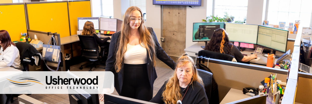 two people one the boss standing one at their cube looking at each other